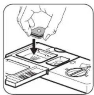 Diagram showing a hand holding a small object above a device with labeled parts and an arrow indicating direction.