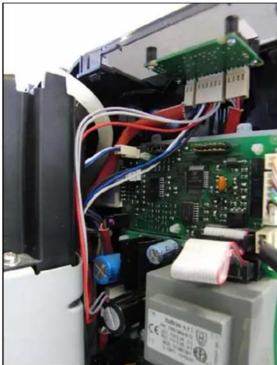 Interior view of an electronic device showing exposed circuit board, capacitors, and wiring (no readable text or symbols)