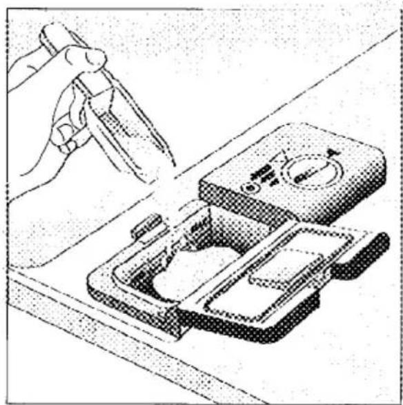 Illustration of a hand using a tool to clean or adjust a device with a control panel (no text or symbols visible)