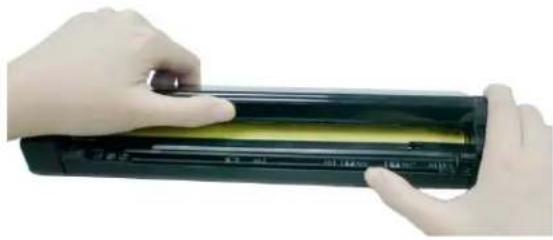 Close-up of hands holding a black cylindrical device with yellow liquid, no visible text or symbols