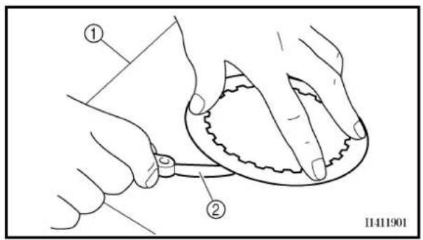Technical diagram showing two hands operating a small object with labeled parts, likely illustrating a procedure or assembly.