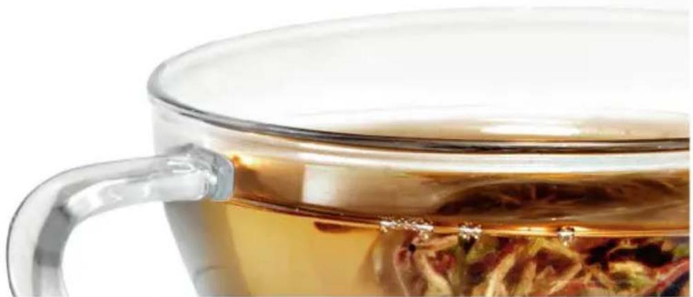 Close-up of a glass mug filled with tea, showing liquid and loose tea leaves (no text or symbols visible)