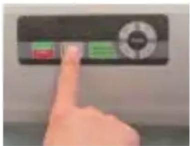 Hand pressing a button on a device with green and red buttons, showing a finger pointing at the button.