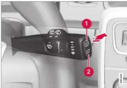 Close-up of a car dashboard control panel with labeled buttons and directional arrows indicating action or movement.