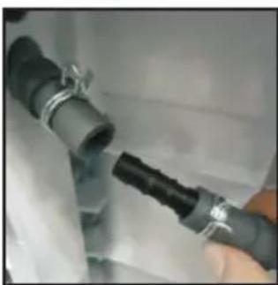 Close-up of a hand holding a black plastic pipe fitting attached to a white surface (no text or symbols visible)