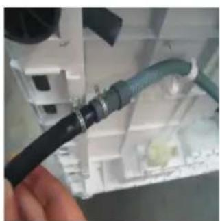 Close-up of a hand holding a black cable with a green cable inserted into a white electrical panel (no visible text or symbols)