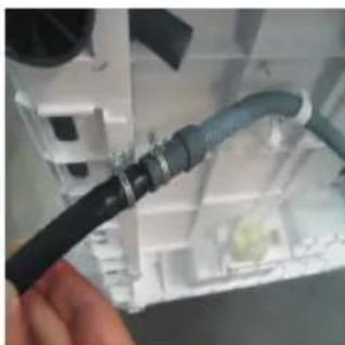 Close-up of a hand holding a black cable with blue insulation, attached to a white industrial device (no visible text or symbols)