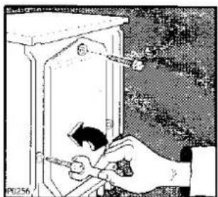 Illustration d'une main utilisant un outil pour ajuster ou installer un dispositif à l'intérieur d'une armoire (aucun texte ou symbole visible)