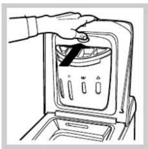 Line drawing of a hand placing a component into a washing machine (no text or symbols)