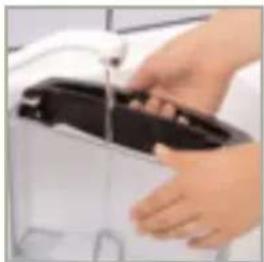 Close-up of hands cleaning a white appliance with a black lid, with no visible text or symbols.