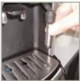Close-up of a hand inserting a small component into a black appliance (no visible text or symbols)