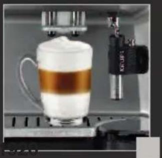 Close-up of a coffee maker machine with a glass mug filled with milk and a brown band, no visible text or symbols.