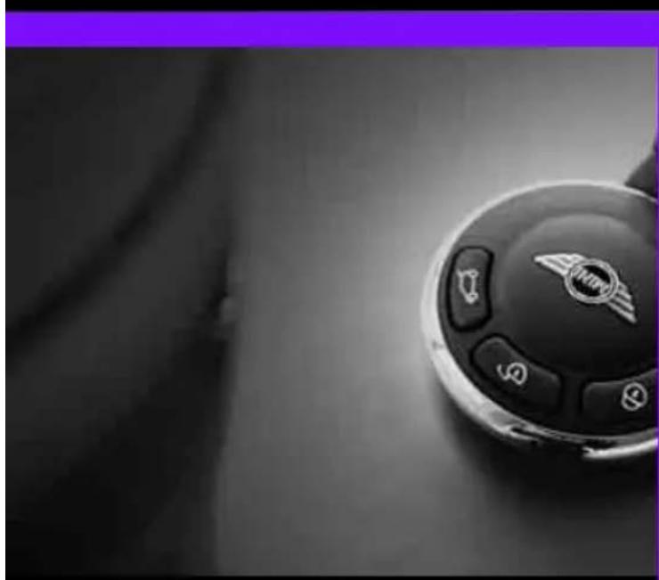 Close-up of a car steering wheel with illuminated buttons and a logo (no readable text or symbols)