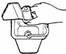 Line drawing of a hand using a tool to lift a component into a container (no text or symbols)
