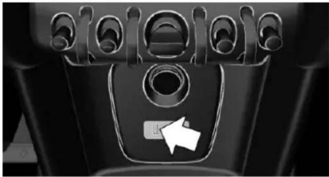 Close-up of a car's front panel with circular buttons and a white directional arrow (no text or symbols)