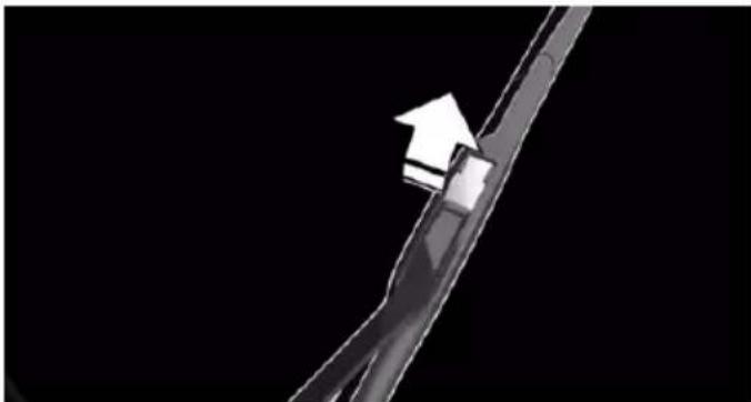 Close-up of a thin metal tool with a white arrow pointing to a small object on the tip, against a black background (no text or symbols)