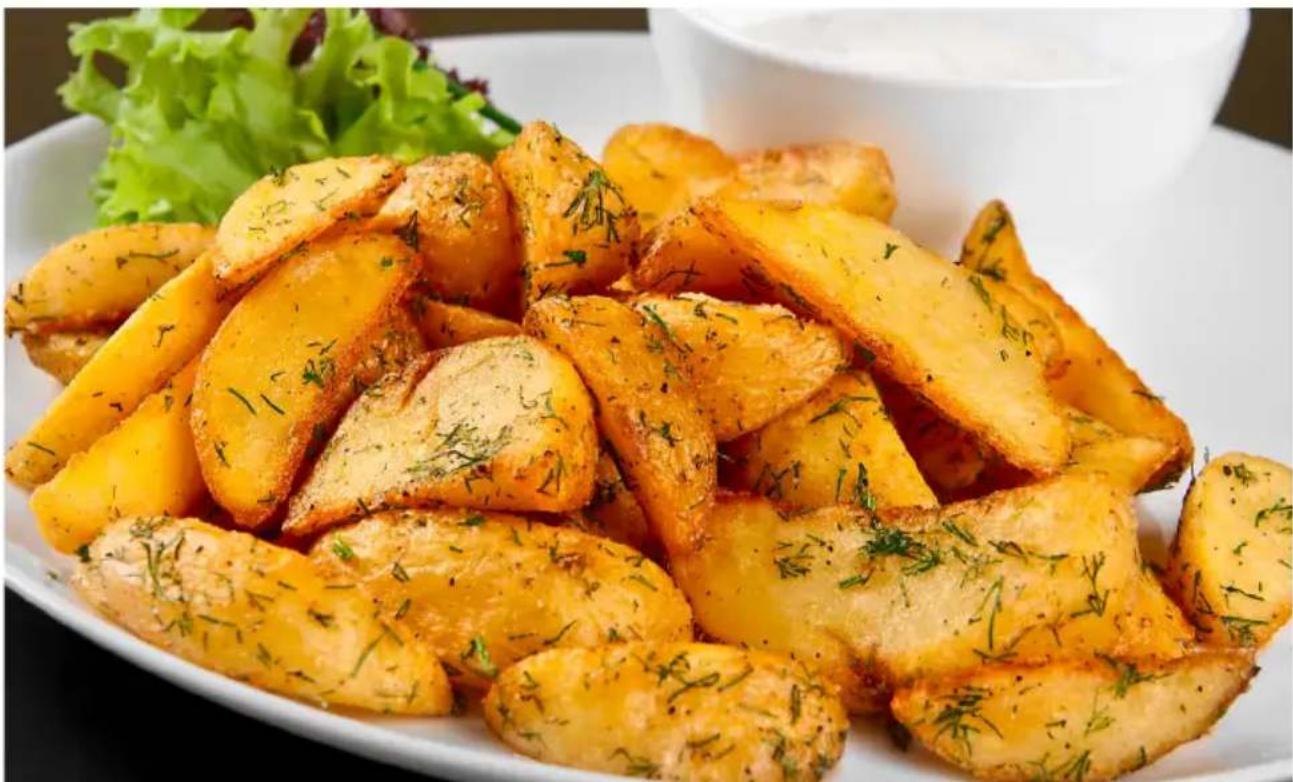 Plate of golden-brown baked potatoes garnished with herbs and lettuce, served on a white dish (no text or symbols visible)