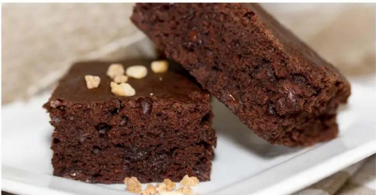 Close-up of two layered chocolate dessert pieces with visible nuts, served on a white plate (no text or symbols)