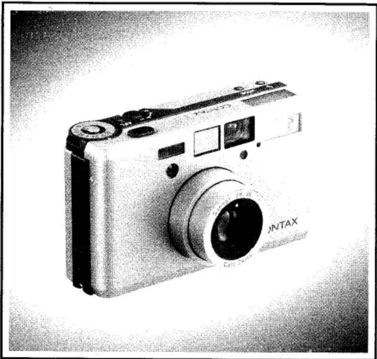Photographie en noir et blanc d'un appareil photo numérique JNTAX avec objectif et panneau de commande (aucun texte ou symbole visible sur le boîtier).