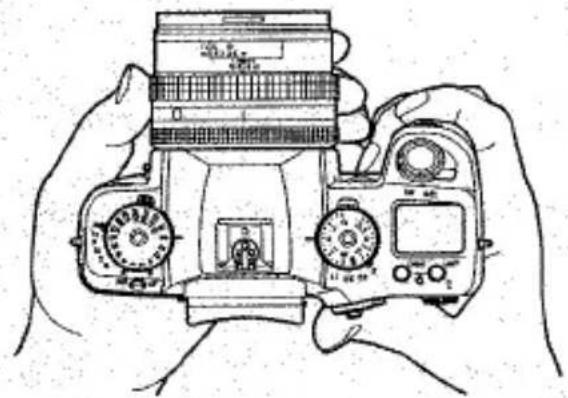 Dessin au trait de mains tenant un appareil photo reflex numérique avec deux molettes et un écran (pas de texte ni de symboles visibles)