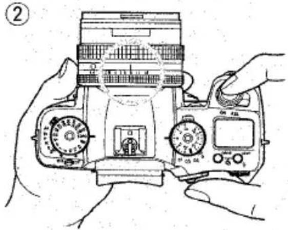 Dessin au trait d'un appareil photo reflex numérique avec double molette et boutons de commande, des mains ajustant l'objectif (sans texte ni symbole).
