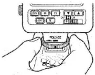 Schéma dessiné à la main montrant une main tenant un appareil avec des boutons étiquetés et un bouton 'RELEASE', illustrant probablement un mécanisme de statut ou de contrôle.