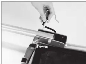 Close-up of a hand holding a small object with a metallic handle, next to a mechanical device (no visible text or symbols)