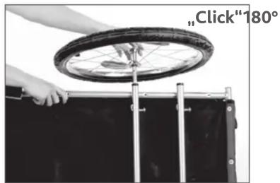 Person using a bicycle wheel to lift a black box, with a metal frame extending horizontally (no text or symbols visible)