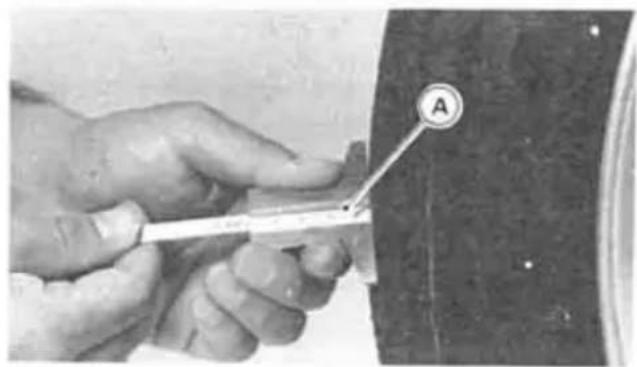 Close-up of hands using a tool to measure a small object, labeled with letter A and number 21.