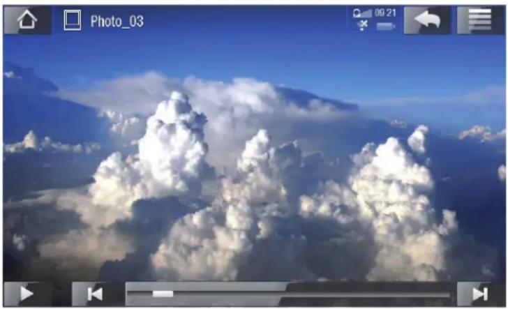 Aerial view of a mountainous landscape with dense clouds rising against a clear blue sky (no text or symbols visible)