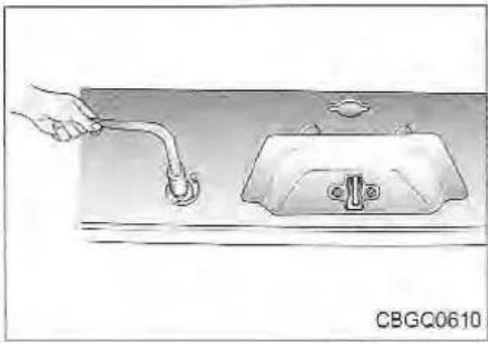 Hand holding a pipe inserted into a water tank (no text or symbols visible)