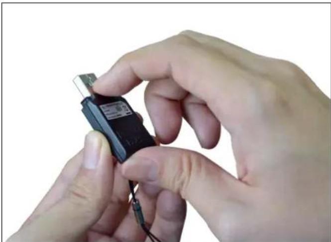 Close-up of hands holding a small electronic device with wires, no visible text or symbols