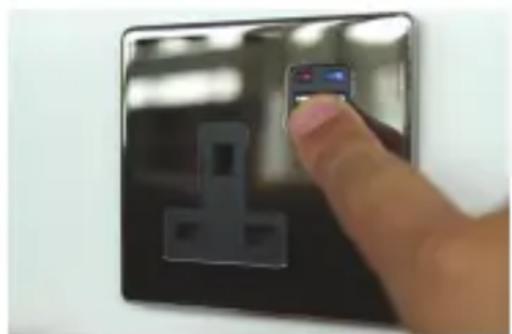 Close-up of a hand holding a small electronic device with a black electrical socket (no visible text or symbols)