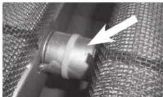 Close-up of a metallic cylindrical component with a white arrow pointing to a small feature, set against a mesh background (no text or symbols visible)