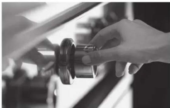 Close-up of a hand adjusting a mechanical component (no visible text or symbols)