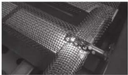 Close-up of a mesh wire mesh structure with a small metallic clip (no text or symbols visible).