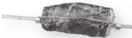 Close-up of a metallic tool holding a textured, irregularly shaped object, no visible text or symbols.