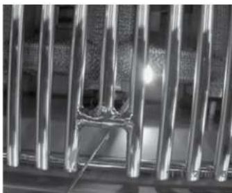 Close-up of metallic vertical rods with a central fracture or indentation, no visible text or symbols