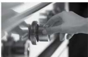 Close-up of a hand holding a small mechanical component, possibly a tool or device, with blurred background (no visible text or symbols)