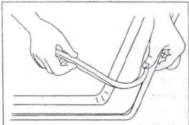 Line drawing of hands holding a tool over a curved object, no text or symbols present.