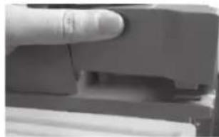 Close-up of a finger pressing down on a mechanical component.