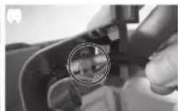 Close-up of a hand holding a mechanical component with a circular inset showing a small object, no visible text or symbols.