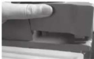 Close-up of a finger pressing down on a mechanical component (no visible text or symbols)
