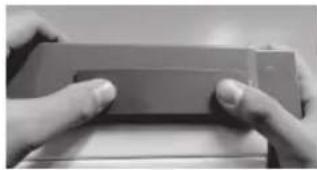 Close-up of hands holding a rectangular object (no visible text or symbols)