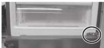 Interior view of a refrigerator with a circular inset showing a small object (no visible text or symbols)