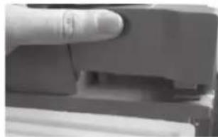 Close-up of a finger pressing down on a mechanical component (no visible text or symbols)