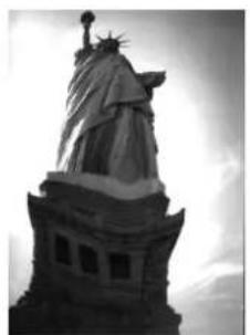 Black-and-white photo of the Statue of Liberty with a tall column and flared pediment (no visible text or symbols).
