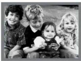 Black-and-white photo of four young children sitting together, smiling (no text or symbols visible)