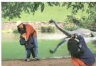 Two people outdoors near a pond, one holding a bird, the other in casual clothing (no visible text or symbols)