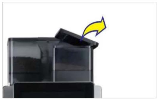Close-up of a black plastic container with a yellow arrow pointing to the lid (no text or symbols visible)